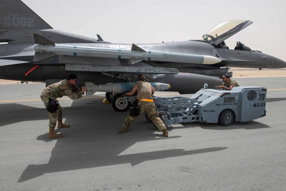 Munitions Specialists from the U.S. Air Force 379th Air Expeditionary Wing load inert munitions onto an F-16 wing on Al Udeid Air Base, Qatar, May 25, 2022. The fighter aircraft landed and was refueled, then loaded with inert explosives to test the capabilities of aircraft refueling and ammo personnel. (U.S. Air National Guard photo by Airman 1st Class Constantine Bambakidis)