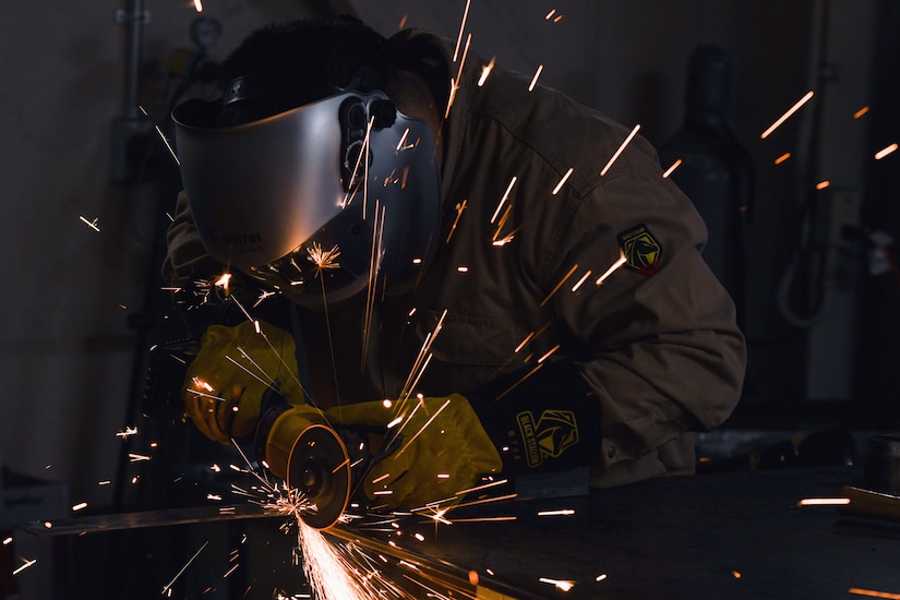 Sparks fly as a sailor welds in a darkened space.