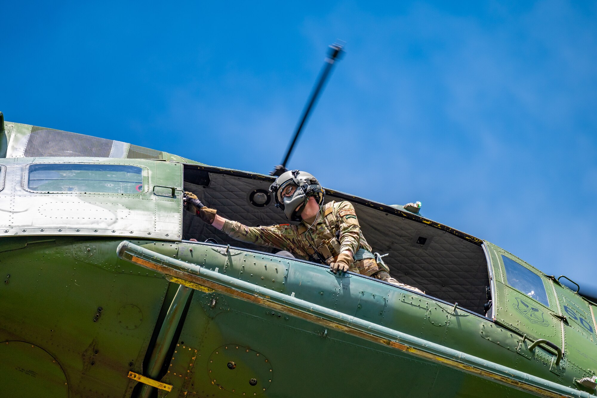 Staff Sgt. Chase Rose, 40th Helicopter Squadron flight engineer, opens the door of a UH-N1 Huey during a search and rescue exercise May 24, 2022, over the Highwood Mountains near Great Falls, Mont.