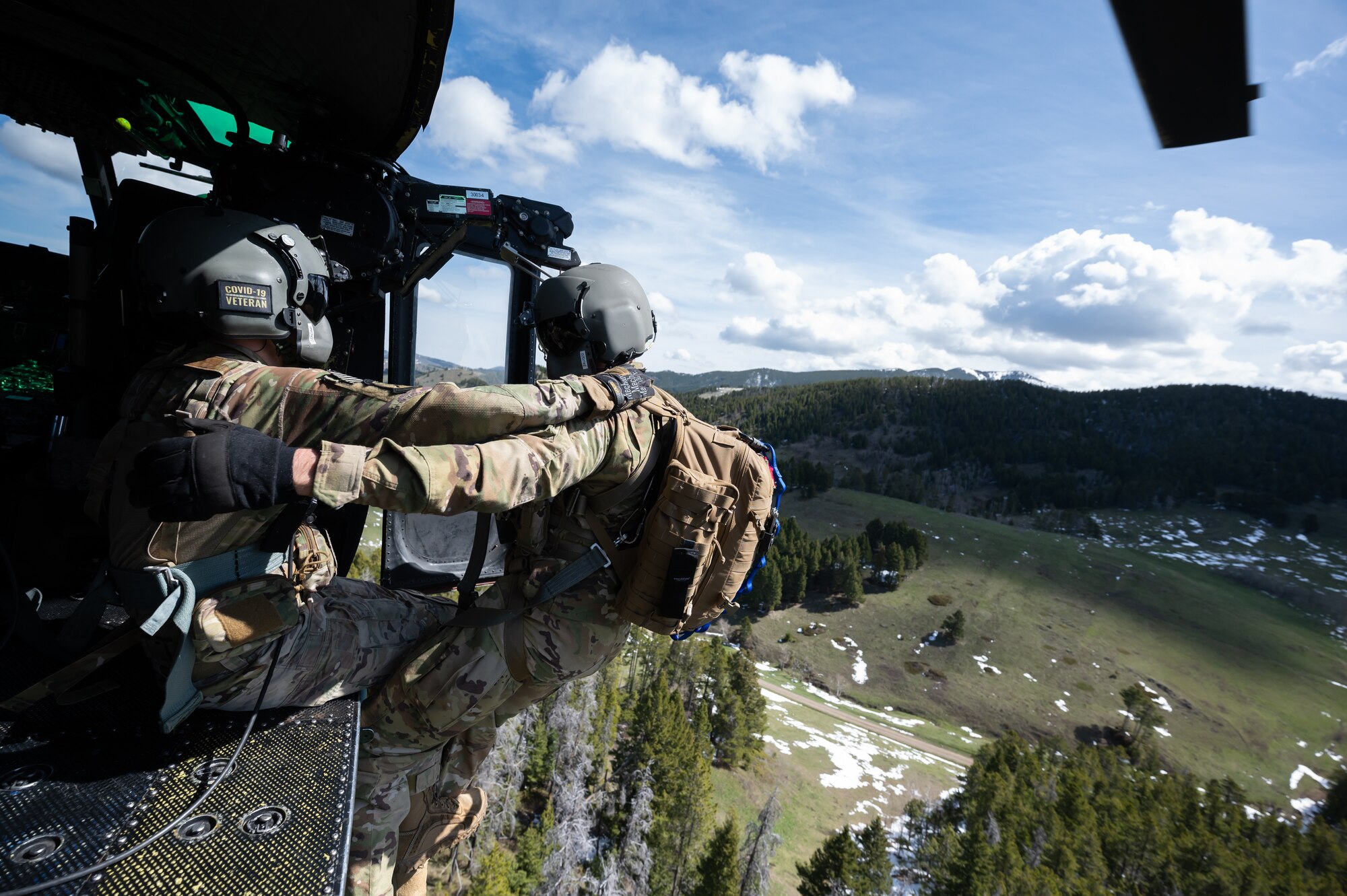 Staff Sgt. Chase Rose, 40th Helicopter Squadron flight engineer, hoists Capt. Noah Russell, 341st Operational Medical Readiness Squadron flight physician, into an UH-1N Huey helicopter during a search and rescue exercise May 24, 2022, over the Highwood Mountains near Great Falls, Mont.