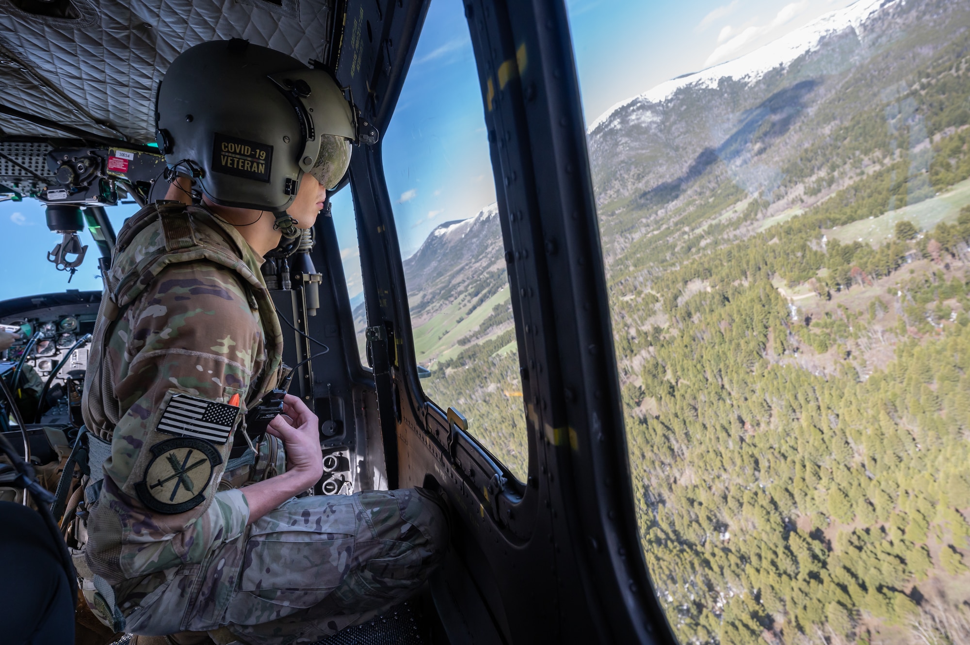 Staff Sgt. Chase Rose, 40th Helicopter Squadron flight engineer, looks out the window of a UH-1N Huey helicopter May 24, 2022, over the Highwood Mountains near Great Falls, Mont.