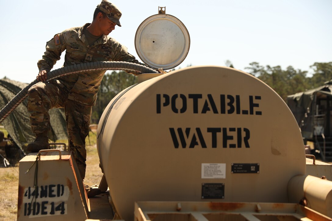 A soldier fills a water tank.