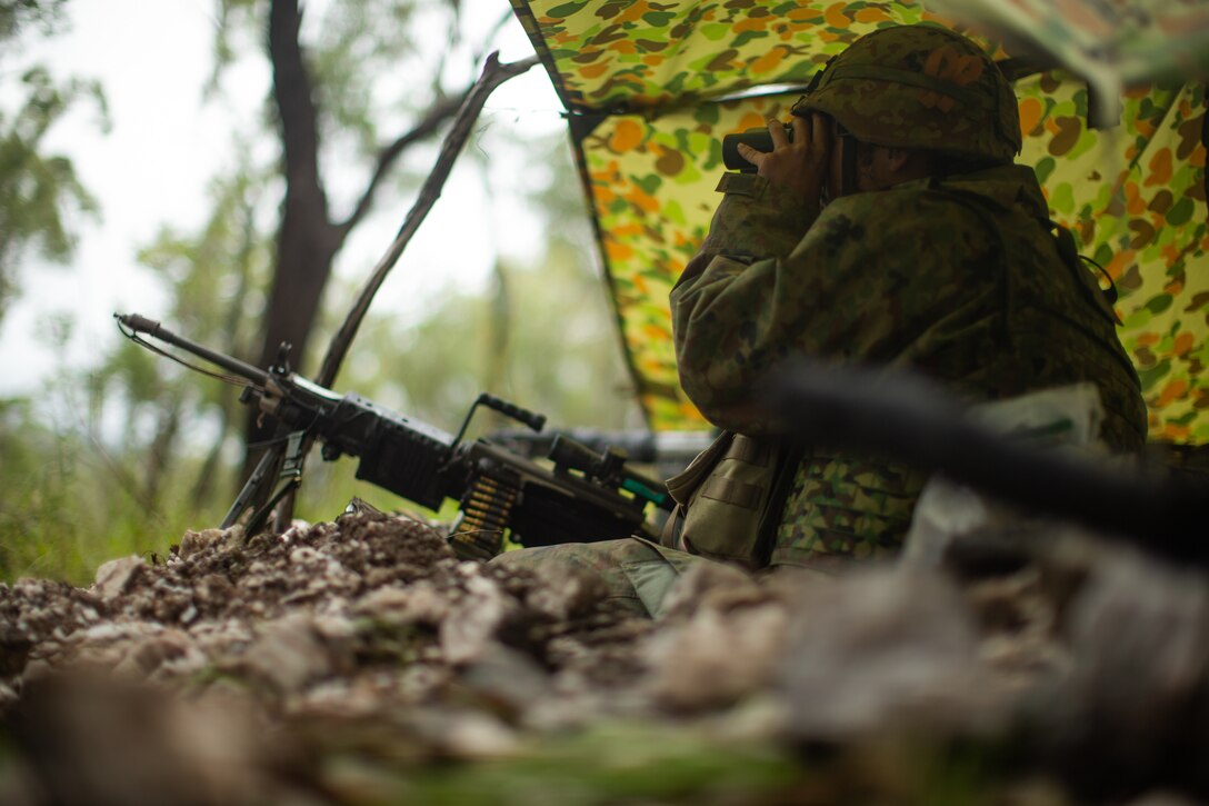 A Japan Ground Self-Defense Force soldier surveys the training area from a defensive position during a simulated combat defense as part of exercise Southern Jackaroo 22 at Shoalwater Bay Training Area, Queensland, Australia, May 21, 2022. Southern Jackaroo is a multilateral exercise carried out by Marines with Marine Rotational Force-Darwin, the Australian Army and JGSDF soldiers, focusing on live-fire and combined arms training. (U.S. Marine Corps Photo by Cpl. Cedar Barnes)