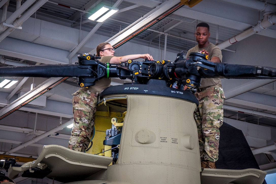 U.S. Army Spc. Kaitlin Cavanaugh and Sgt. Omar Sewell conduct maintenance on the forward rotor of a CH-47 Chinook helicopter that was battle damaged from a hard landing while serving in Iraq in the maintenance bay of the Connecticut National Guard's 1109th Theater Aviation Support Maintenance Group in Groton, Conn. June 22, 2021. The TASMG recovered this helicopter from Kuwait and performed a complete overhaul of the aircraft in order to get it back into the Army's operational fleet.