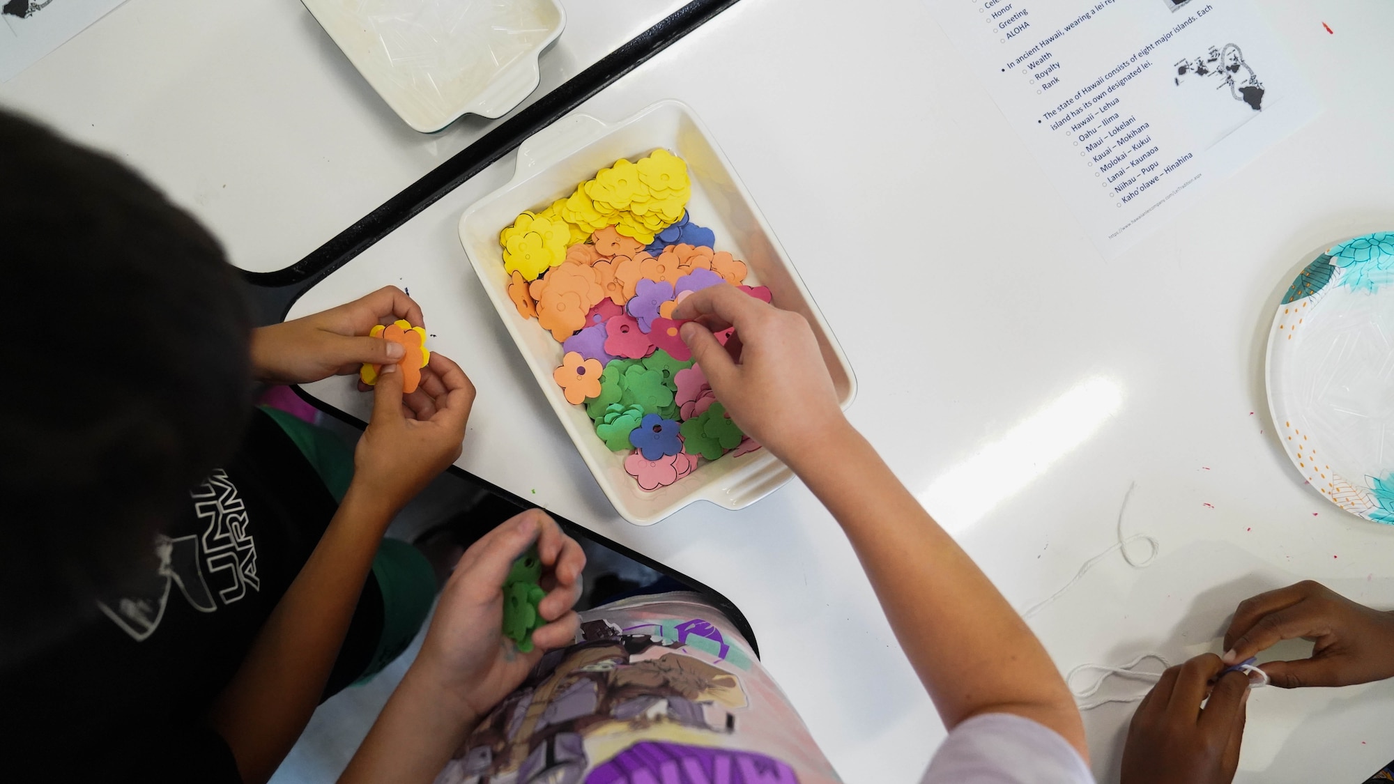 Children assemble paper leis at a event held at the Youth Center on Keesler Air Force Base, Mississippi, May 26, 2022. The Asian American and Pacific Islander Heritage Month committee hosted a craft event to introduce children to AAPI traditions and heritage. (U.S. Air Force photo by Airman 1st Class Elizabeth Davis)