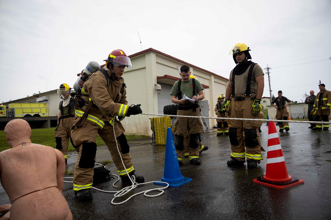 U.S. service members with Headquarters and Headquarters Squadron, Marine Corps Air Station Futenma, Marine Corps Installations Pacific, monitor a rope pulling event during a firefighter Physical Ability Test on Marine Corps Air Station Futenma, Okinawa, Japan, May 4, 2022. The firefighters’ Physical Ability Test is a tool used to measure how effective a Marine is while performing multiple tasks over a set period. The test consists of 10 tasks that evaluate cardiovascular and strength performance. (U.S. Marine Corps photo by Lance Cpl. Jonathan Beauchamp)