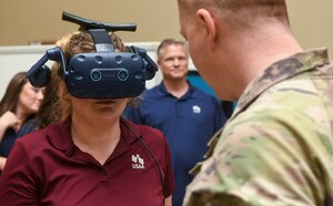 A USAA employee wears a virtual reality headset while Maj. Paul Lentz, 433rd Operations Group chief of innovation, explains it’s capabilities at Joint Base San Antonio-Lackland, Texas, May 17, 2022. The headset allowed the participants to view a virtual model of the C-5M Super Galaxy. (U.S. Air Force photo by Airman 1st Class Mark Colmenares)