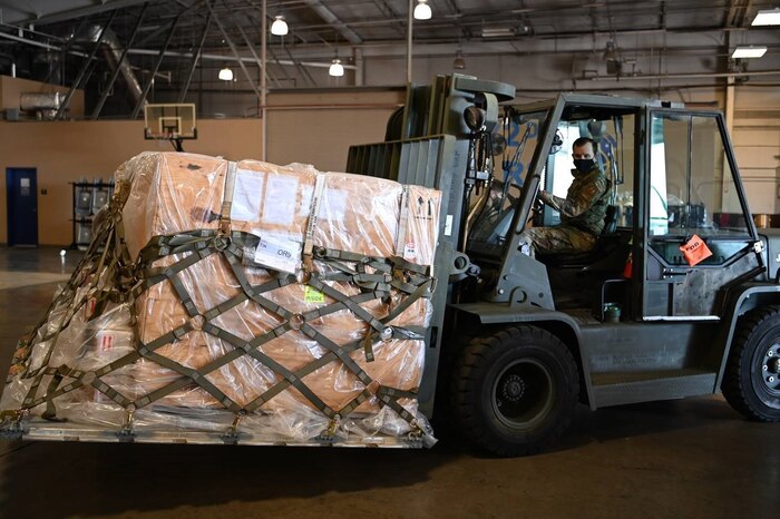SSgt. Bryan Tisdale drives a fork lift moving humanitarian package onto K-Loader.