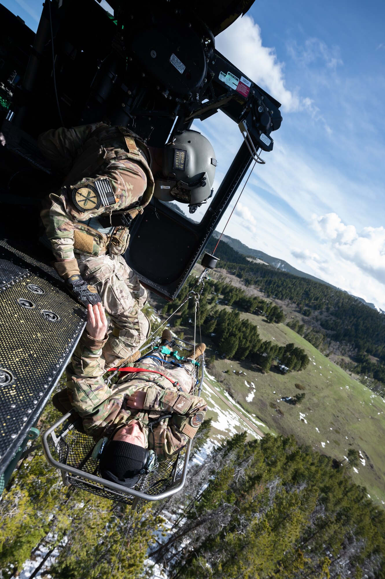 Staff Sgt. Chase Rose, 40th Helicopter Squadron flight engineer, hoists Airman 1st Class Courage Krueger, 341st Contracting Squadron contracting apprentice, into an UH-1N Huey helicopter during a search and rescue exercise May 24, 2022, over the Highwood Mountains near Great Falls, Mont.