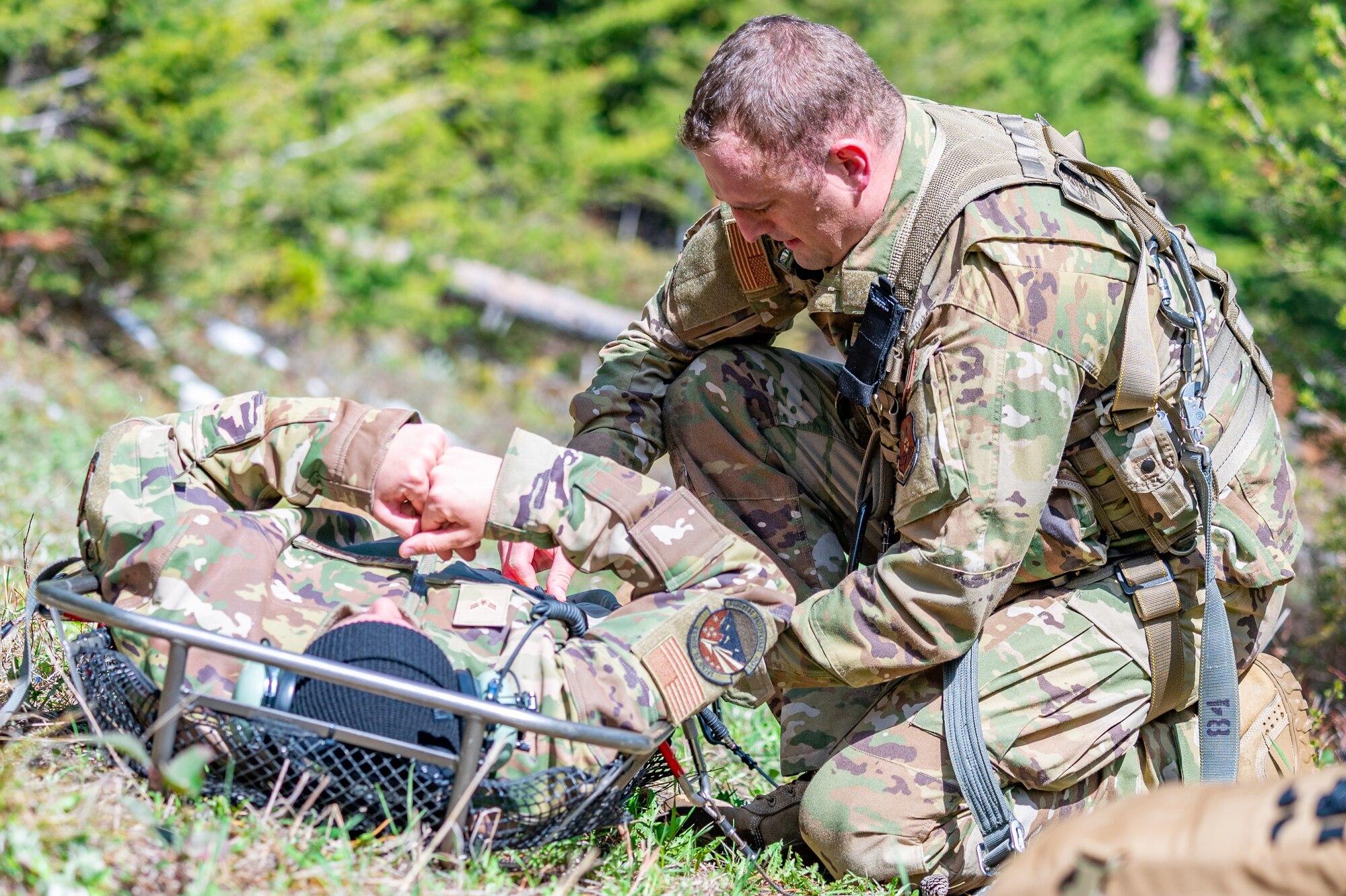 Capt. Noah Russell, 341st Operational Medical Readiness Squadron flight medic, secures Airman 1st Class Courage Krueger, 341st Contracting Squadron contracting apprentice, into a stokes litter during a search and rescue exercise May 24, 2022, over the Highwood Mountains near Great Falls, Mont.