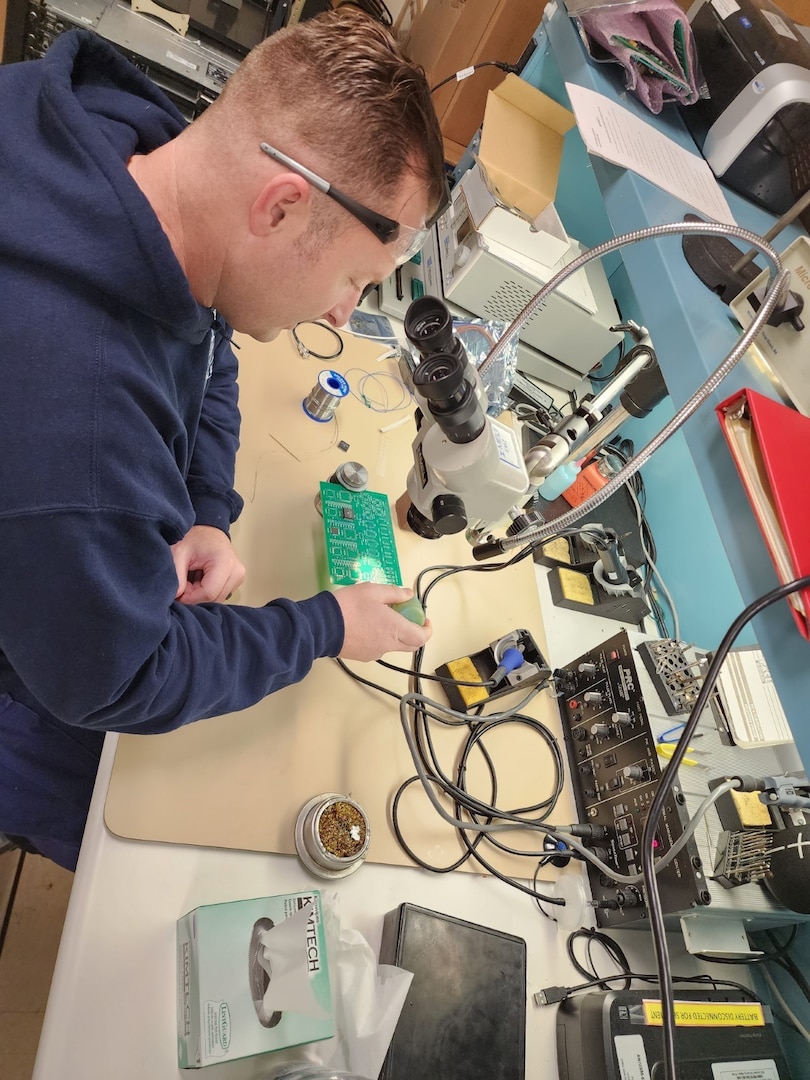 A technician works on a circuit board during recertification training at Coast Guard Electronics Repair Facility IERF) on Sep. 21, 2022. This will enable him to diagnose and perform repairs on miniature and microminiature components of electronics systems. (U.S. Coast Guard photo by Senior Chief Petty Officer Shelldon Green.)