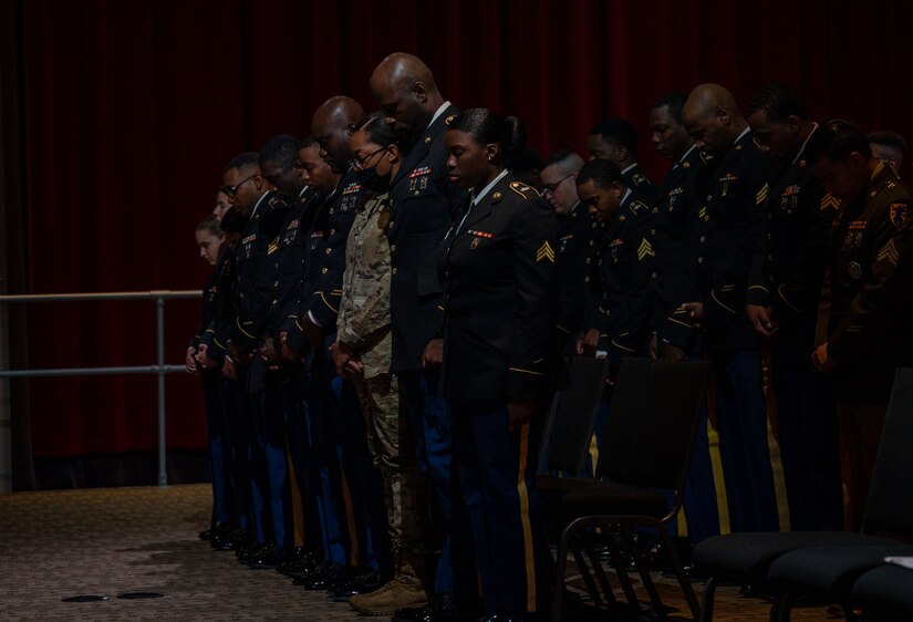 Service members bow their heads during the invocation