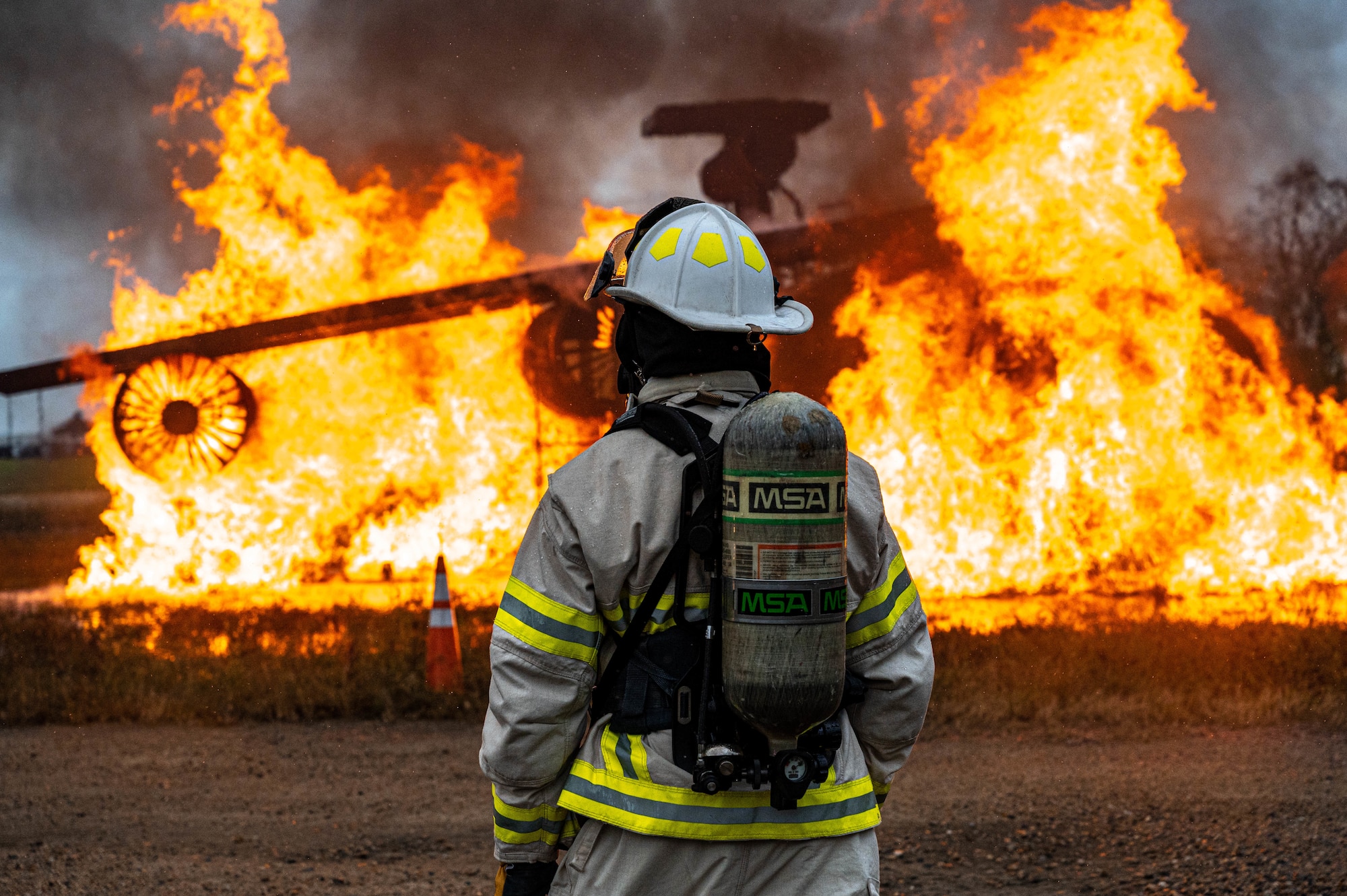 U.S. Air Force Master Sgt. Bryan Senecal, 633d Civil Engineer Squadron firefighter, stares down the flames engulfing the small aircraft trainer during a fire exercise at Joint Base Langley-Eustis, Virginia, Oct. 13, 2022.