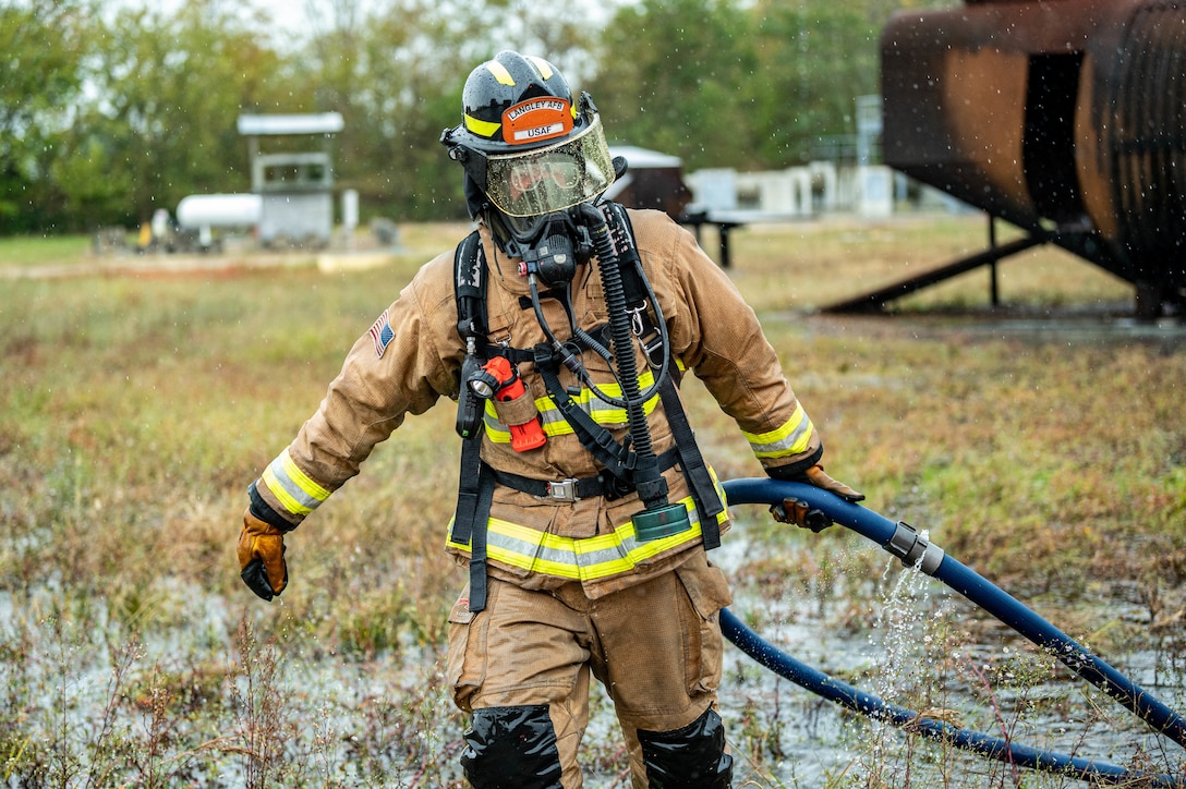 - U.S. Air Force Senior Airman Christopher Parks, 633d Civil Engineer Squadron firefighter, wades through water and tall grass to put the hose away after taking part in successfully putting out the fire on a small aircraft trainer during an exercise at Joint Base Langley-Eustis, Virginia, Oct. 13, 2022.