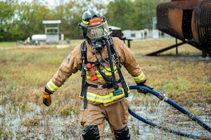 - U.S. Air Force Senior Airman Christopher Parks, 633d Civil Engineer Squadron firefighter, wades through water and tall grass to put the hose away after taking part in successfully putting out the fire on a small aircraft trainer during an exercise at Joint Base Langley-Eustis, Virginia, Oct. 13, 2022.