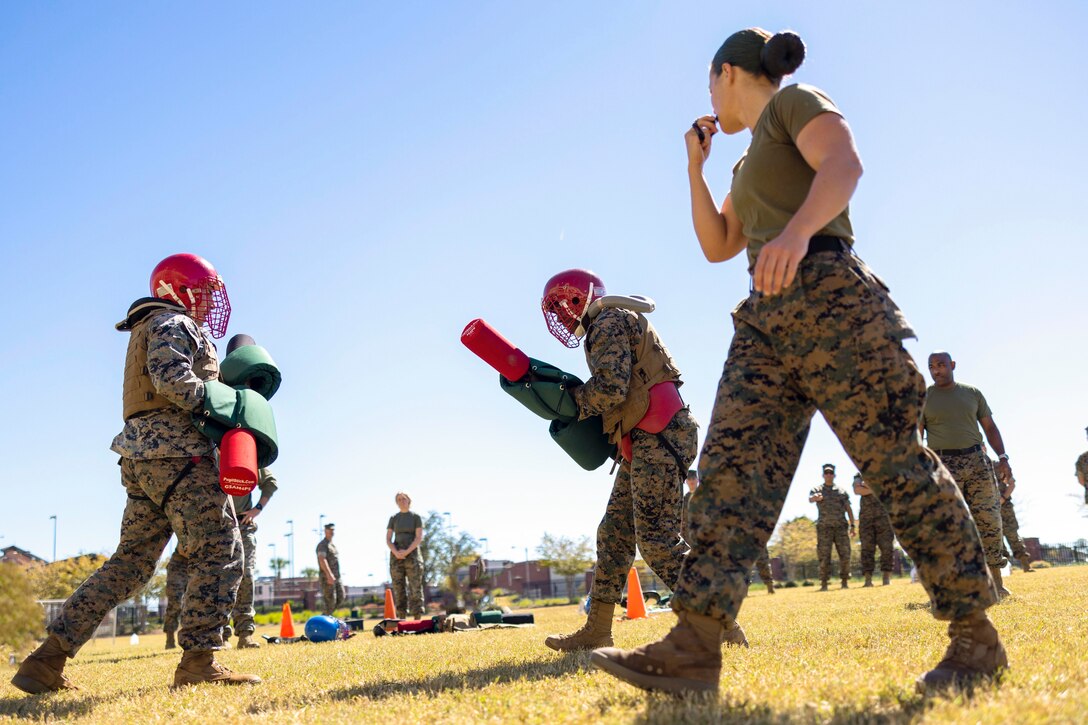 Marines compete in a pugil stick competition as a fellow Marines watch.