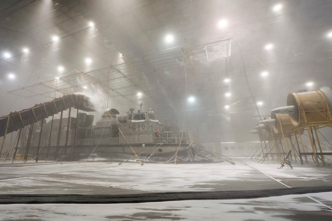 Water falls onto a small boat in a warehouse with a white substance on the ground.