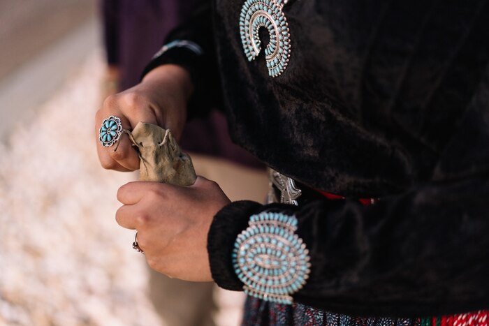 A woman takes a pinch of corn pollen from a pouch