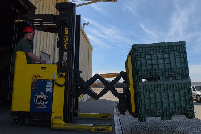 Mr. Corey Roach, 9th Logistics Readiness Squadron Materiel Handler, lifts two large crates full of cold weather gear to the deployment and distribution site