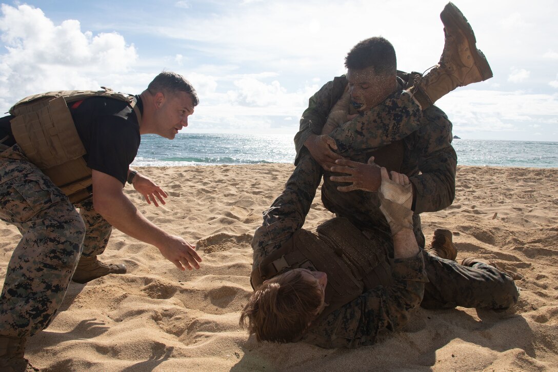 U.S. Marine Corps Gunnery Sgt. Matthew Dennis, instructor, Marine Corps Martial Arts, 1st Battalion 12th Marines, left, oversees two Marines grappling during a Marine Corps Martial Arts Instructor Course culminating event, Marine Corps Base Hawaii, Oct. 06, 2022.