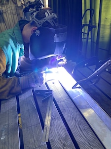 Project Arc Engineer 1st Lt. Andrew Foor welds together supporting parts for the hardening of a low-cost threat emitter Oct. 18, 2022, at Luke Air Force Base, Arizona. Foor, an electrical engineer by trade, worked with his teammate to help Luke Air Force Base modernize its ranges with emerging, high-impact technologies. (U.S. Air Force photo)