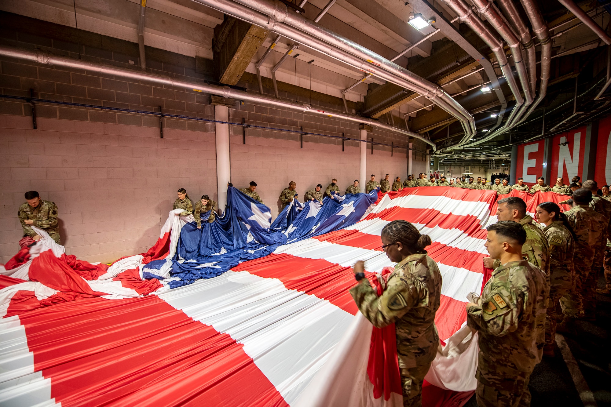 Airmen from the 501st Combat Support Wing, fold an American flag prior to a national anthem demonstration at Wembley Stadium, in London, England, Oct. 30, 2022. Approximately 70 uniformed personnel represented the U.S. Air Force and nation by unveiling an American flag during the pre-game ceremonies of the Jacksonville Jaguars and Denver Broncos NFL game. (U.S. Air Force photo by Staff Sgt. Eugene Oliver)