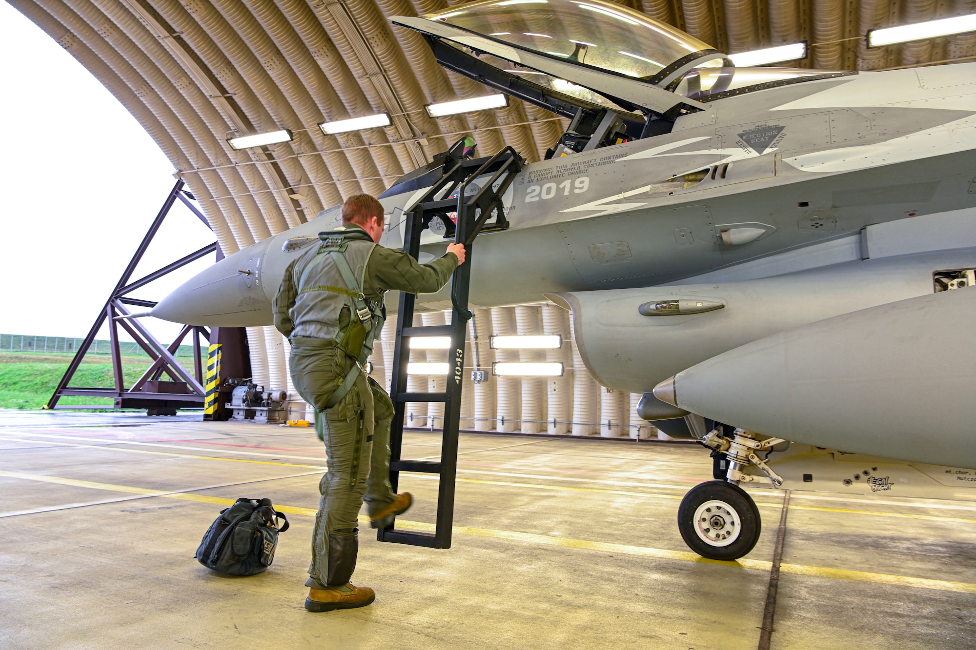 Pilot climbing ladder into F-16