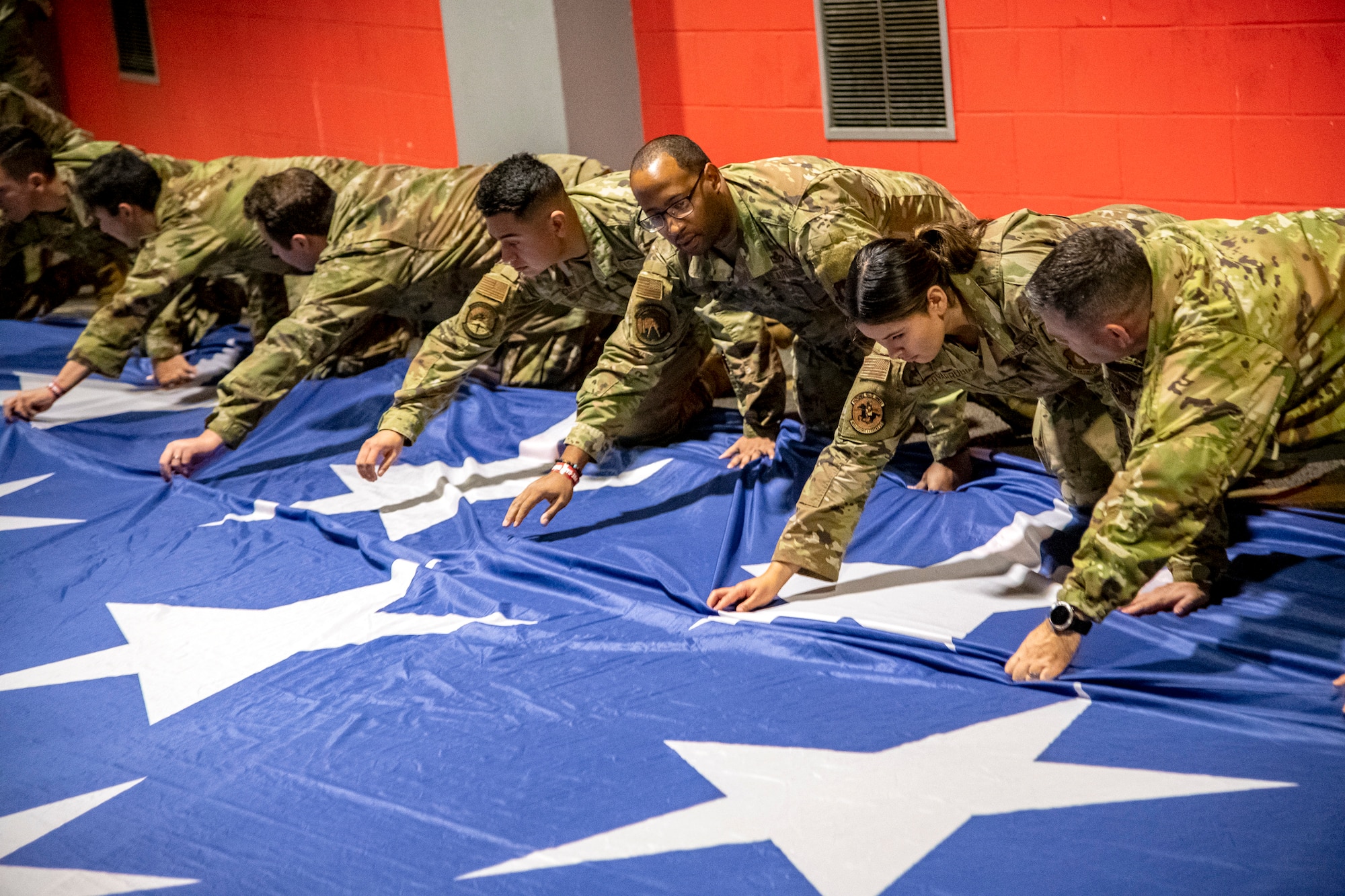 Airmen from the 501st Combat Support Wing grab the seam of an American flag at Wembley Stadium, in London, England, Oct. 30, 2022. Approximately 70 uniformed personnel represented the U.S. Air Force and nation by unveiling an American flag during the pre-game ceremonies of the Jacksonville Jaguars and Denver Broncos NFL game. (U.S. Air Force photo by Staff Sgt. Eugene Oliver)