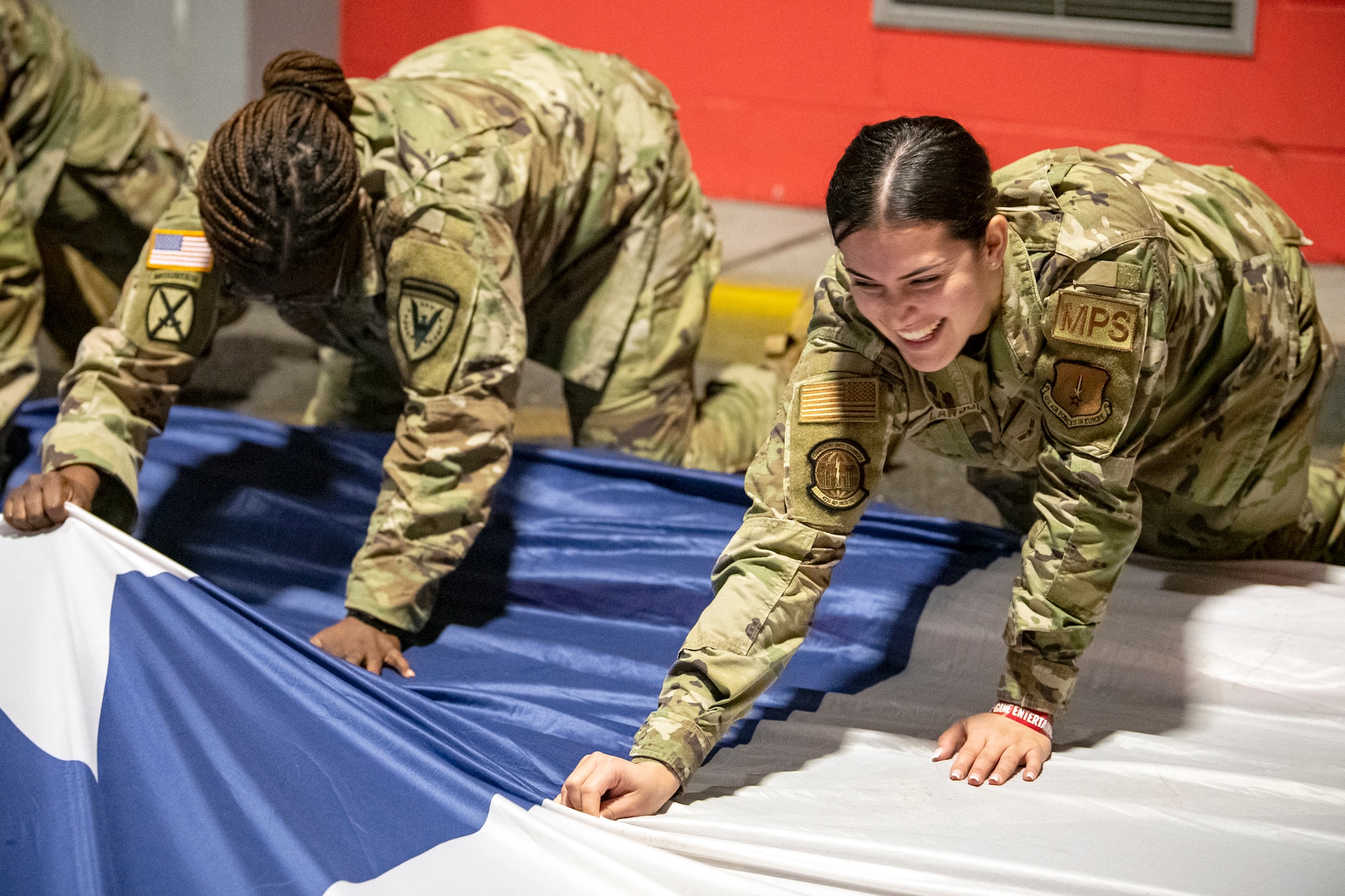 U.S. Air Force Airman 1st Class Kennedy Lawson, right, 422d Air Base Squadron postal clerk, grabs the seam of an American flag at Wembley Stadium, in London, England, Oct. 30, 2022. Approximately 70 uniformed personnel represented the U.S. Air Force and nation by unveiling an American flag during the pre-game ceremonies of the Jacksonville Jaguars and Denver Broncos NFL game. (U.S. Air Force photo by Staff Sgt. Eugene Oliver)