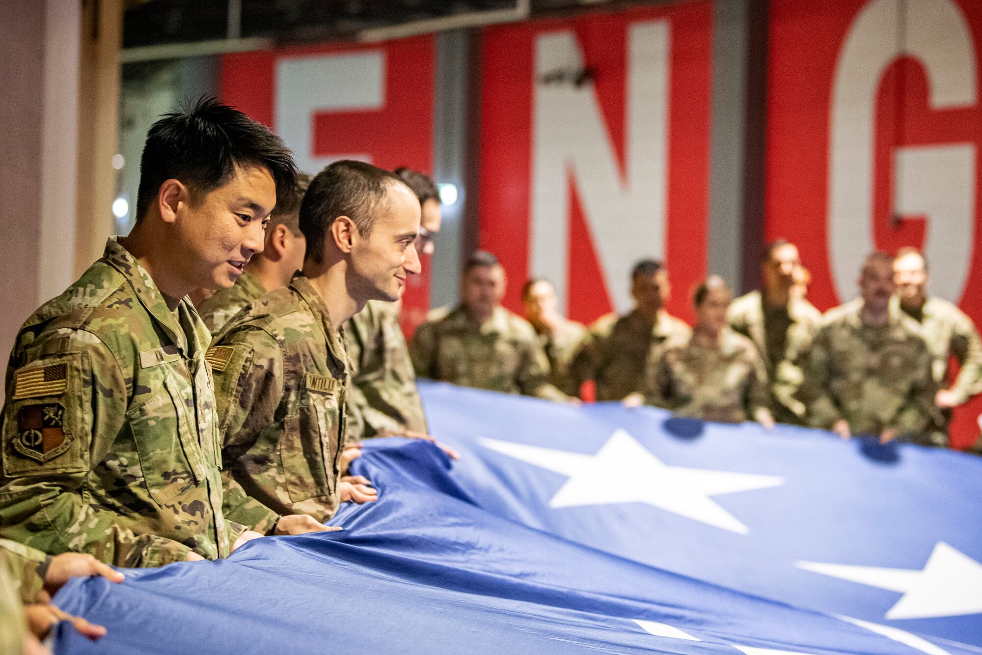 U.S. Air Force Staff Sgt. Jae Yen Kim, left, 501st Combat Support Wing resource advisor, holds an American flag along with Airmen from the 501st CSW, at Wembley Stadium, in London, England, Oct. 30, 2022. Approximately 70 uniformed personnel represented the U.S. Air Force and nation by unveiling an American flag during the pre-game ceremonies of the Jacksonville Jaguars and Denver Broncos NFL game. (U.S. Air Force photo by Staff Sgt. Eugene Oliver)
