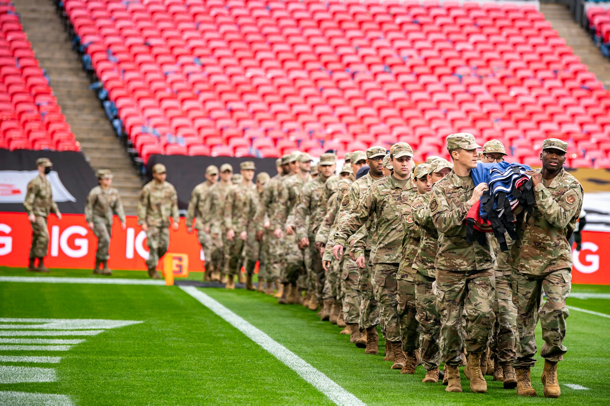 Airmen from the 501st Combat Support Wing carry an American flag onto the field during national anthem rehearsal at Wembley Stadium, in London, England, Oct. 30, 2022. Approximately 70 uniformed personnel represented the U.S. Air Force and nation by unveiling an American flag during the pre-game ceremonies of the Jacksonville Jaguars and Denver Broncos NFL game. (U.S. Air Force photo by Staff Sgt. Eugene Oliver)
