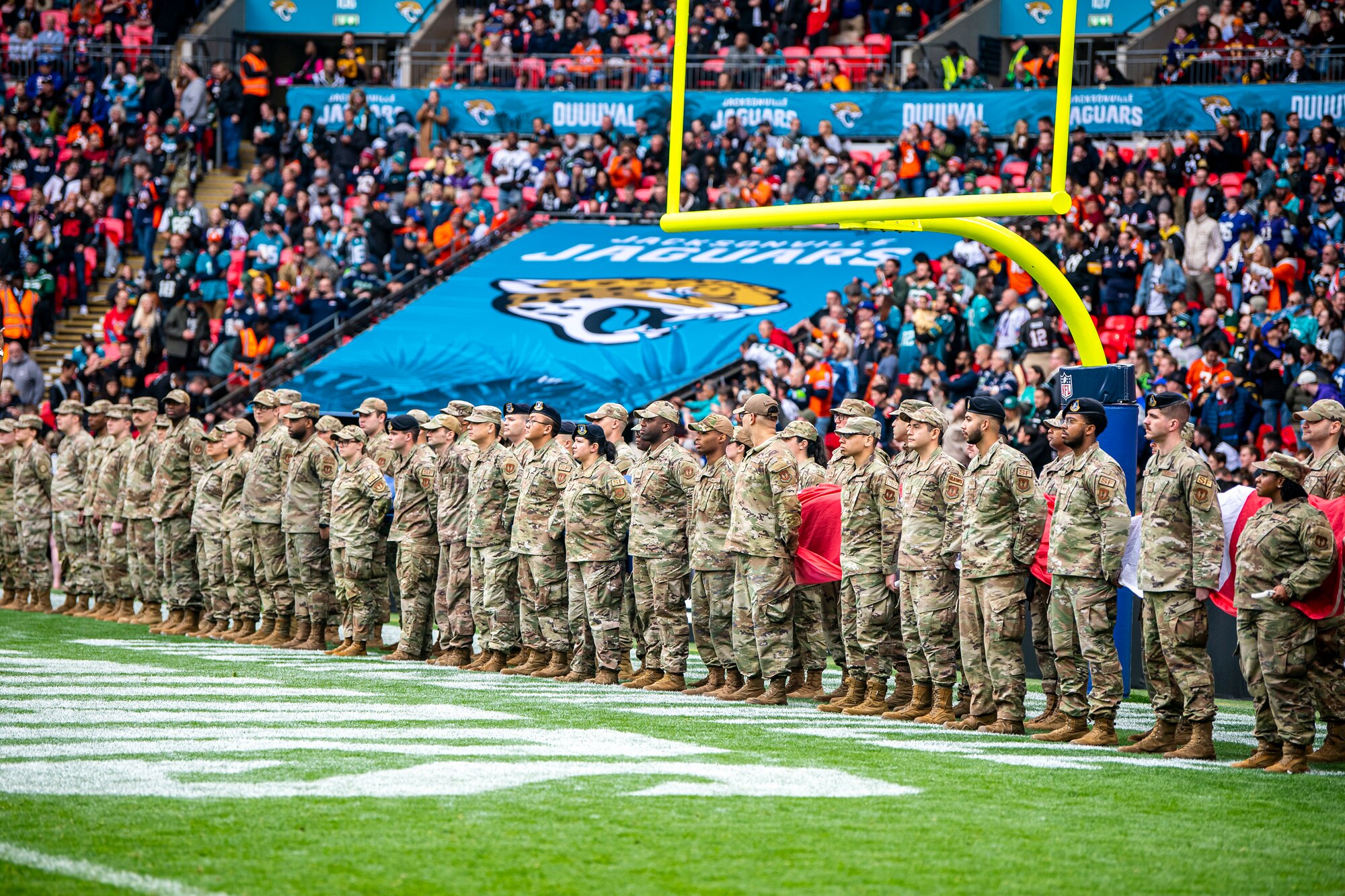 Airmen from the 501st Combat Support Wing stand at attention prior to the national anthem at Wembley Stadium, in London, England, Oct. 30, 2022. Approximately 70 uniformed personnel represented the U.S. Air Force and nation by unveiling an American flag during the pre-game ceremonies of the Jacksonville Jaguars and Denver Broncos NFL game. (U.S. Air Force photo by Staff Sgt. Eugene Oliver)