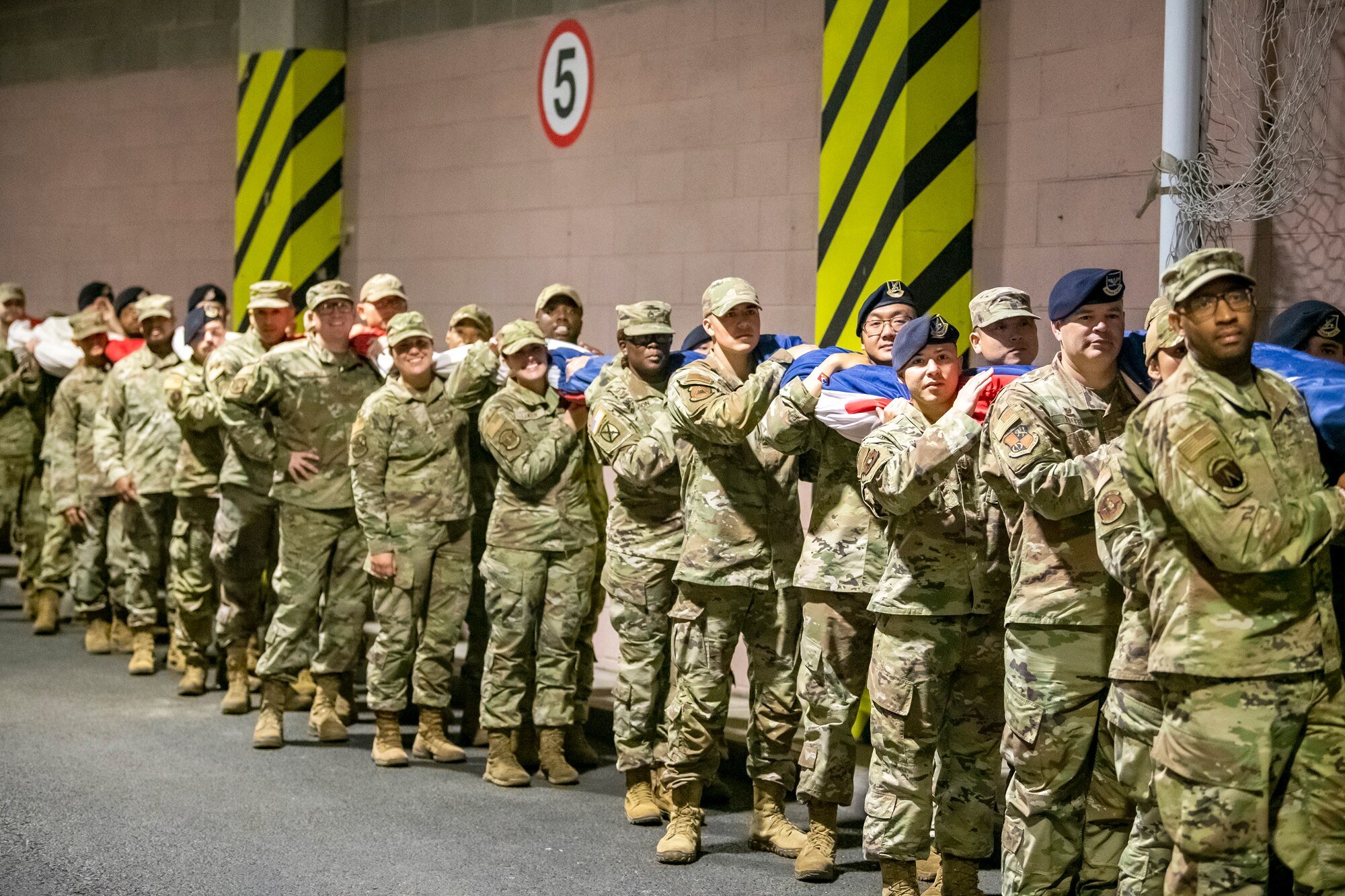 Airmen from the 501st Combat Support Wing hold an American Flag prior to the national anthem at Wembley Stadium, in London, England, Oct. 30, 2022. Approximately 70 uniformed personnel represented the U.S. Air Force and nation by unveiling an American flag during the pre-game ceremonies of the Jacksonville Jaguars and Denver Broncos NFL game. (U.S. Air Force photo by Staff Sgt. Eugene Oliver)