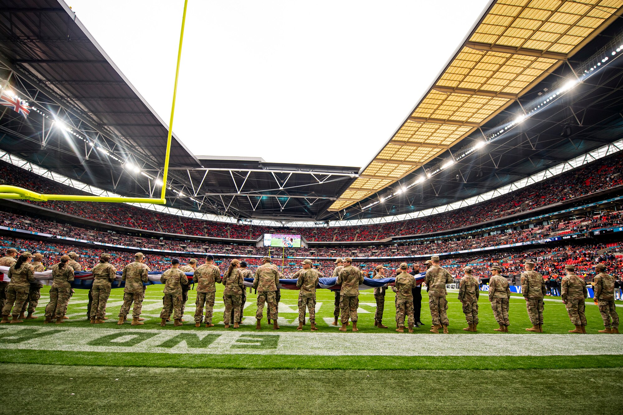 Airmen from the 501st Combat Support Wing hold an American flag prior to the national anthem at Wembley Stadium, in London, England, Oct. 30, 2022. Approximately 70 uniformed personnel represented the U.S. Air Force and nation by unveiling an American flag during the pre-game ceremonies of the Jacksonville Jaguars and Denver Broncos NFL game. (U.S. Air Force photo by Staff Sgt. Eugene Oliver)