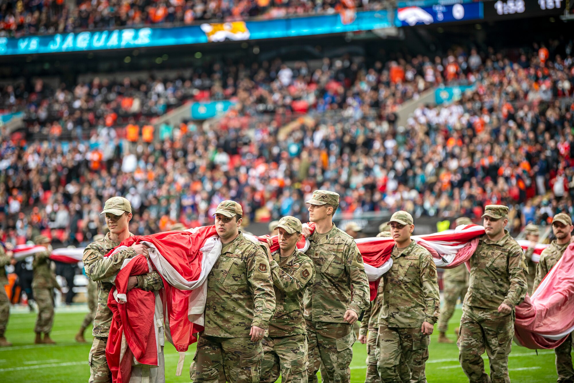 Airmen from the 501st Combat Support Wing carry an American flag off the field following the national anthem at Wembley Stadium, in London, England, Oct. 30, 2022. Approximately 70 uniformed personnel represented the U.S. Air Force and nation by unveiling an American flag during the pre-game ceremonies of the Jacksonville Jaguars and Denver Broncos NFL game. (U.S. Air Force photo by Staff Sgt. Eugene Oliver)