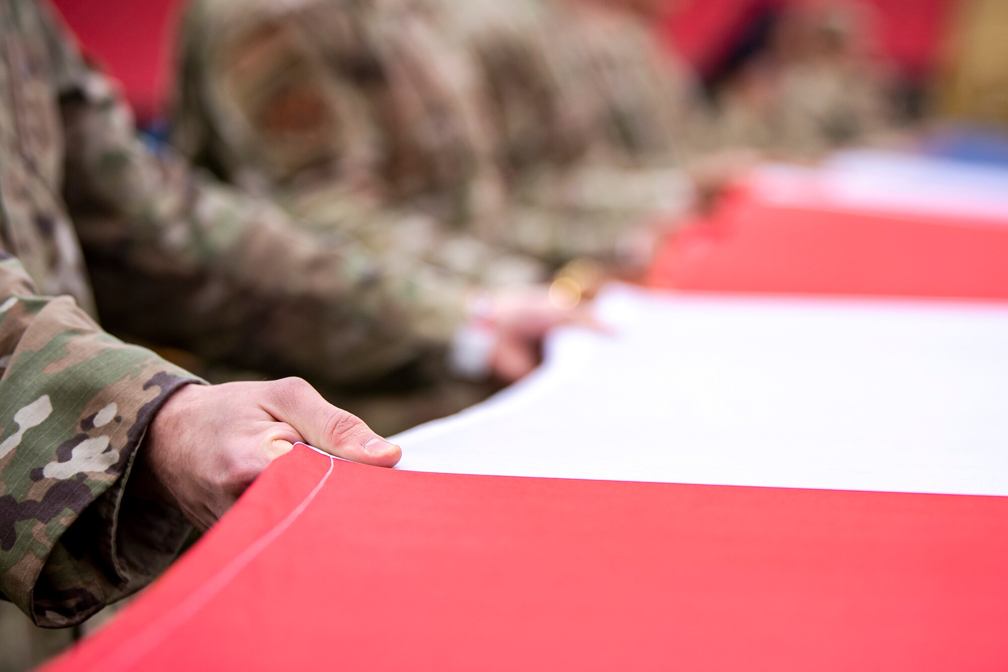 An Airman from the 501st Combat Support Wing hold an American flag during the national anthem at Wembley Stadium, in London, England, Oct. 30, 2022. Approximately 70 uniformed personnel represented the U.S. Air Force and nation by unveiling an American flag during the pre-game ceremonies of the Jacksonville Jaguars and Denver Broncos NFL game. (U.S. Air Force photo by Staff Sgt. Eugene Oliver)