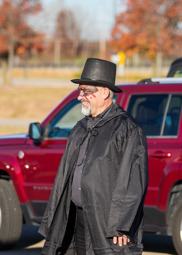 A man in black cape, black hat, and black clothes with black make up on.