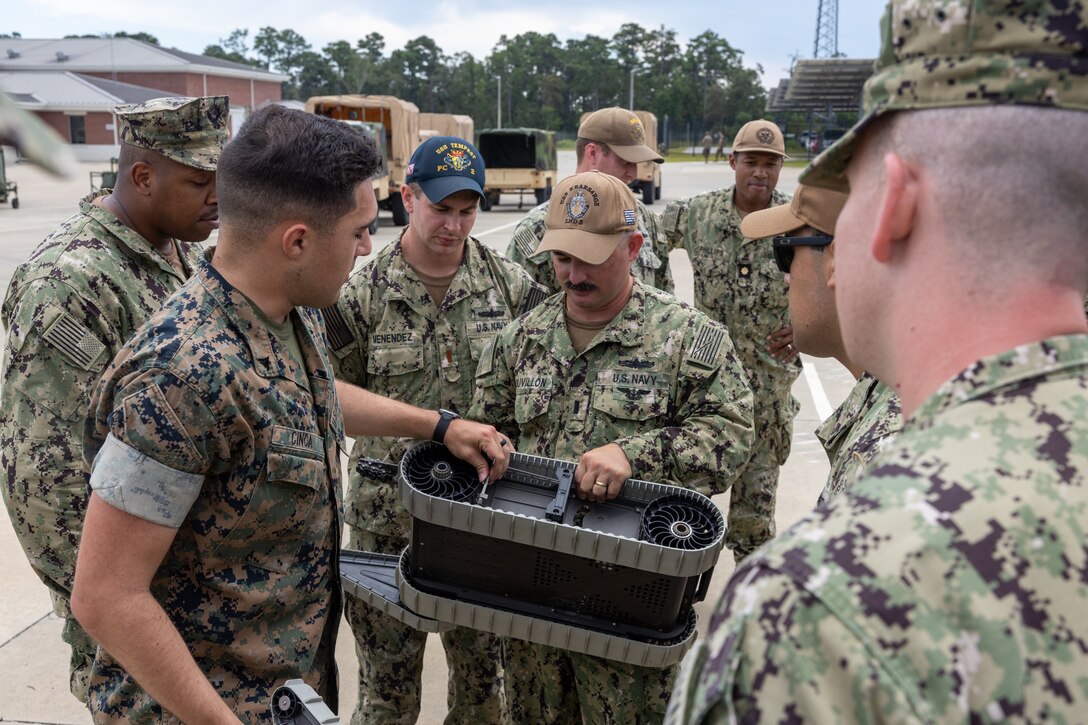 U.S. Navy personnel with U.S. Navy Amphibious Warfare Tactics Instructor Course receive a capability brief on a Micro Tactical Ground Explosive Ordnance Disposal Robot from a Marine with Light Armored Reconnaissance Battalion, 2nd Marine Division on September 7-8, 2022, on Marine Corps Air Station New River and Marine Corps Base Camp Lejeune, North Carolina. II MEF units gave AMW-WTI students capability briefs in order to familiarize them with the landward environment, planning considerations, and exposure to all the elements of the Fleet Marine Force.
