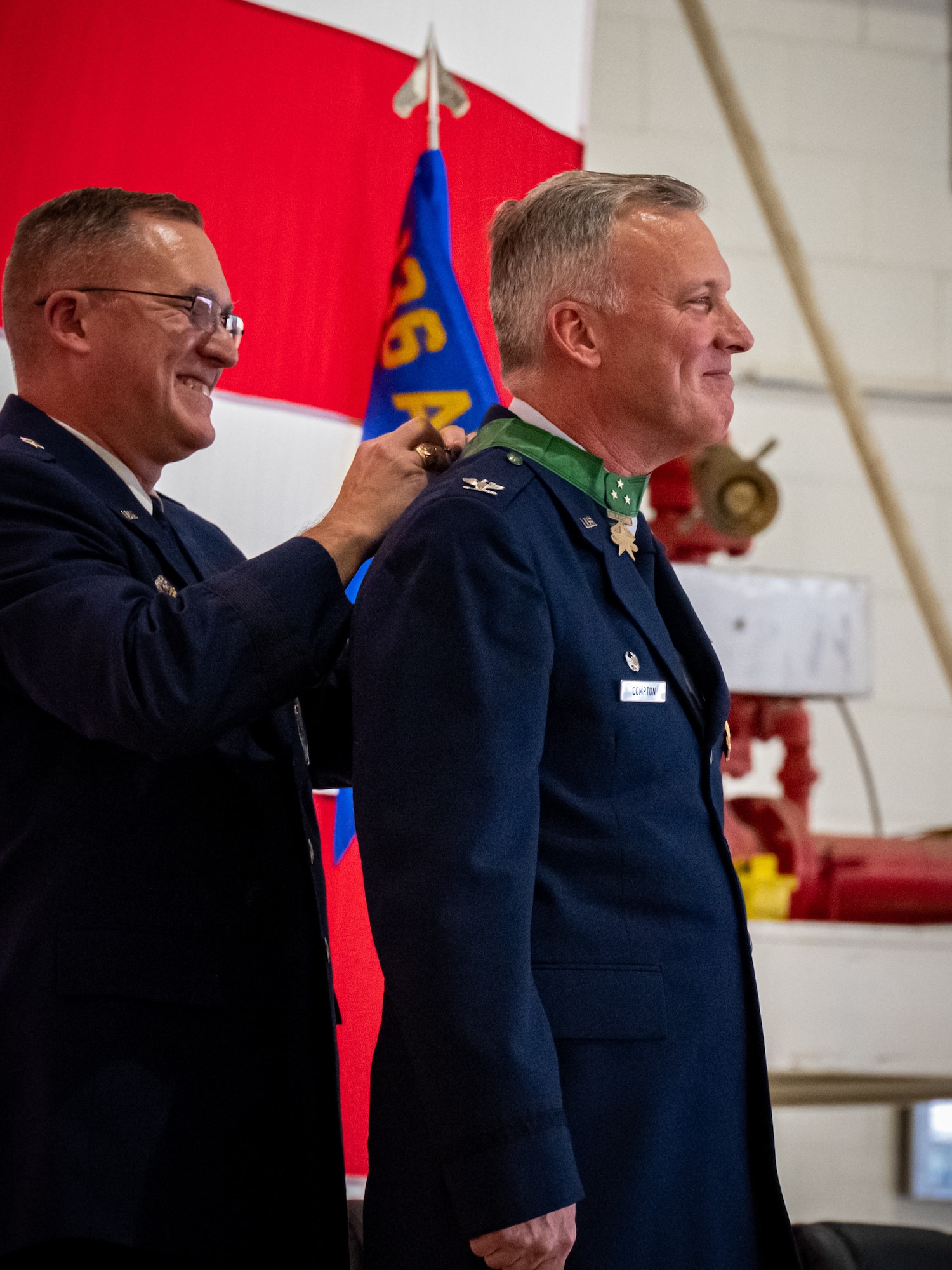General fastens a medal around the neck of a retiring officer.