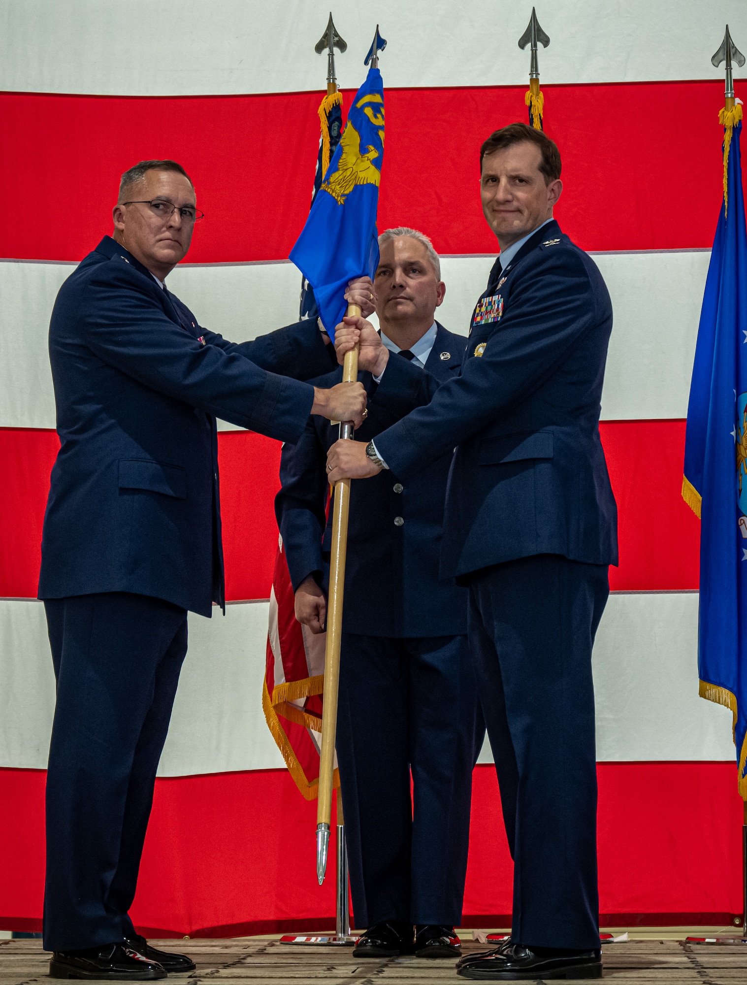 Two Air National Guard officers hold military unit guidon flag.