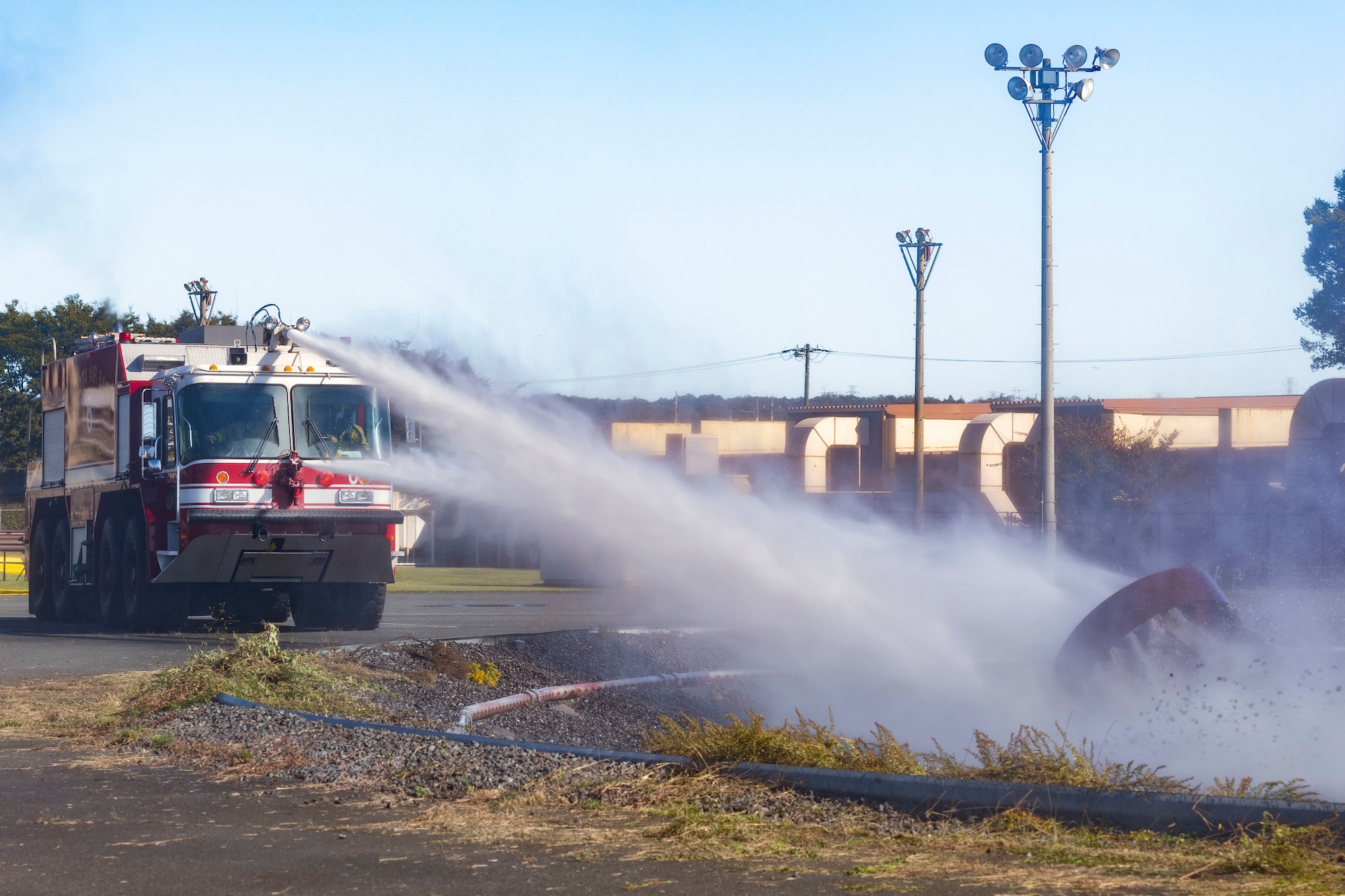 Firefighters from the 374th Civil Engineer Squadron use fire truck water cannons to put out an aircraft fire simulator during a bilateral training session with Japan Air Self-Defense Force firefighters at Yokota Air Base, Japan, Oct. 26, 2022.