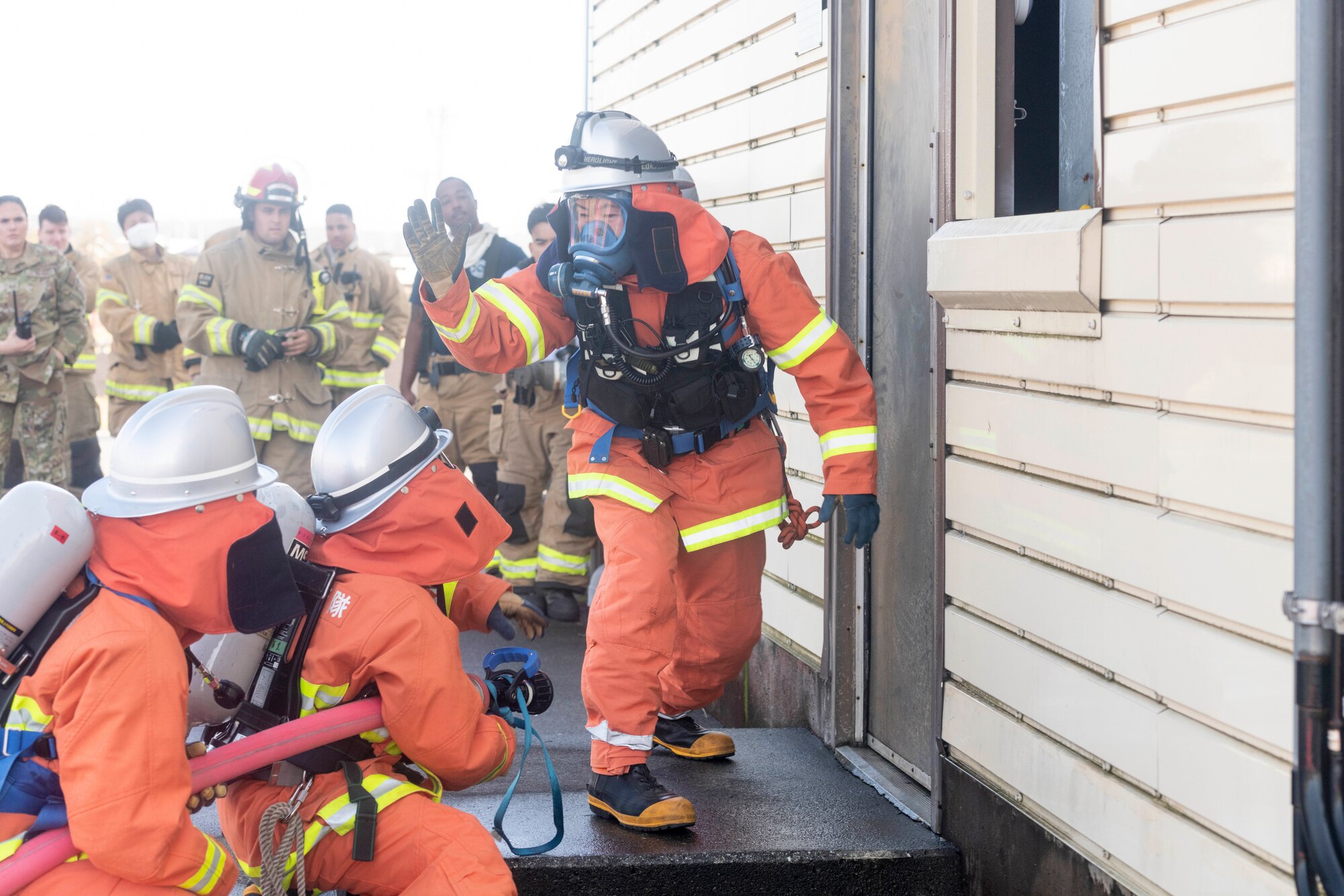 A firefighter with the Japanese Air Self-Defense Force gives hand signals to members of his team during a bilateral training at Yokota Air Base, Japan, Oct. 28, 2022.