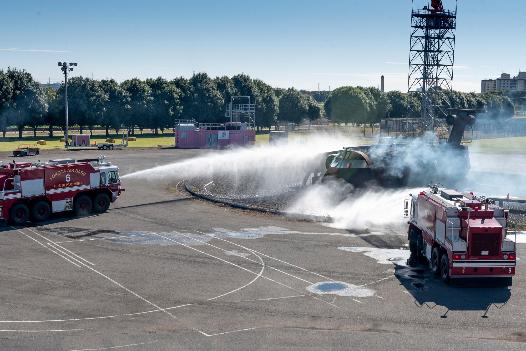 Firefighters from the 374th Civil Engineer Squadron use fire truck water cannons to put out an aircraft fire simulator during a bilateral training session with Japan Air Self-Defense Force firefighters at Yokota Air Base, Japan, Oct. 26, 2022.