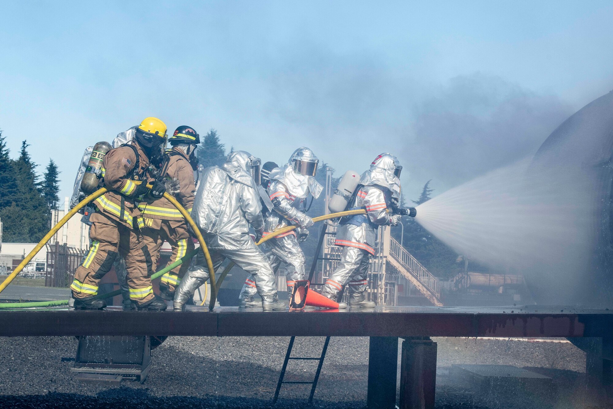 Firefighters from the Japanese Air Self-Defense Force and 374th Civil Engineer Squadron team up to spray water on a simulated aircraft fire during a bilateral training at Yokota Air Base, Japan, Oct. 26, 2022.