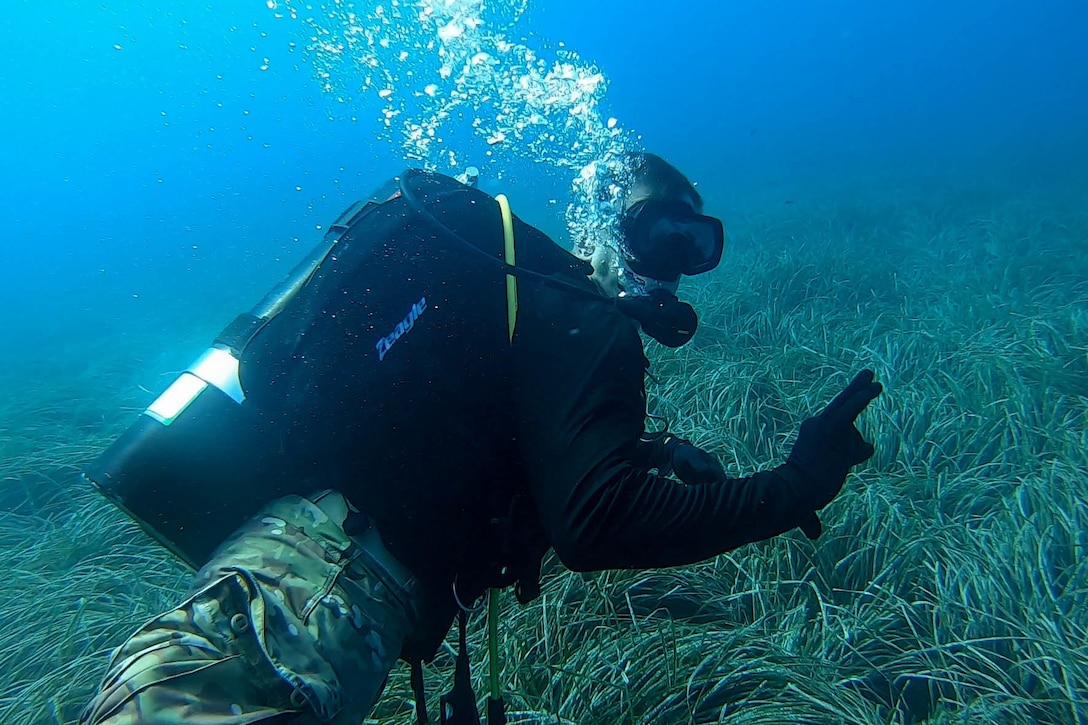 A soldier swims underwater.