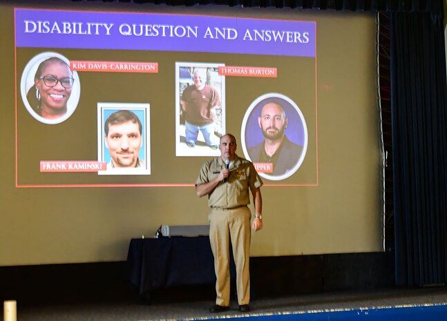 IMAGE: Naval Surface Warfare Center Dahlgren Division (NSWCDD) Capt. Philip Mlynarski speaks during the National Disability Employment Awareness Month commemoration Oct. 28 at the Naval Support Facility Dahlgren base theater. Disabled U.S. Department of Defense employees (left to right on the screen) Kim Davis-Carrington, Frank Kaminski, Thomas Burton and James Skipper told their stories of how various disabilities have impacted them at work and socially during the mostly virtual event.