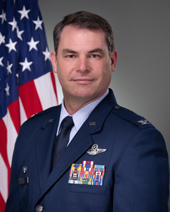 Col Scott Meyer in front of a grey background with an American flag.