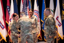 three people standing in front of a row of flags pass a flag