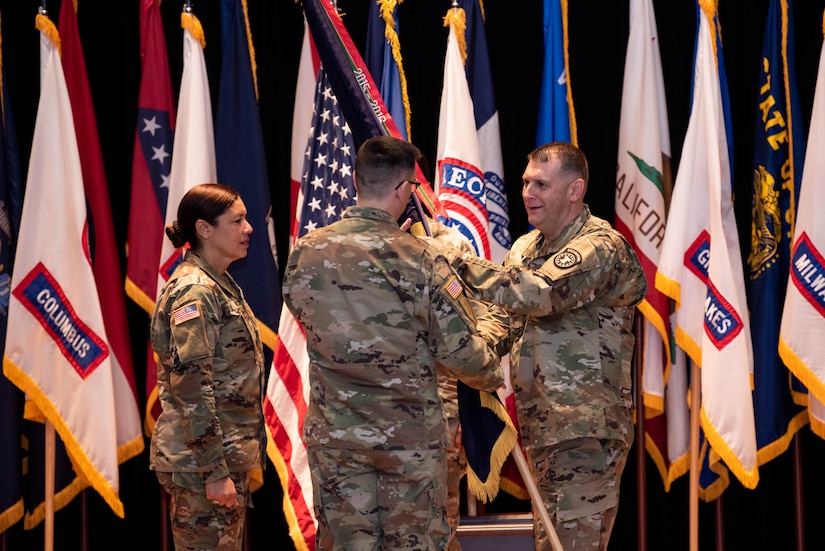 three people standing in front of a row of flags pass a flag