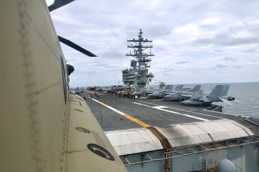 Aircraft sit in a row on the deck of a ship.